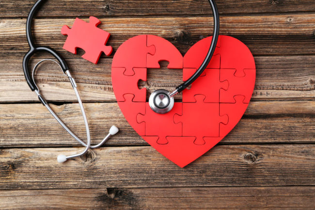 39253427 – red puzzle heart with stethoscope on brown wooden background